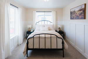 Bedroom featuring multiple windows and light colored carpet