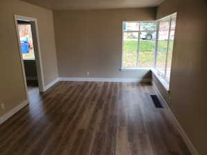 Spare room with a textured ceiling, a wealth of natural light, and dark wood-type flooring