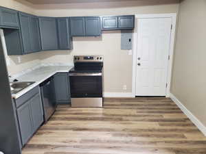 Kitchen with appliances with stainless steel finishes, electric panel, light hardwood / wood-style flooring, and sink