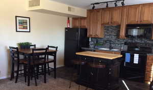 Kitchen featuring black appliances, butcher block countertops, sink, and tasteful backsplash