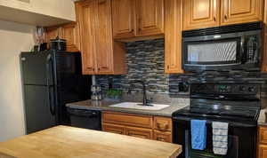 Kitchen featuring sink, tasteful backsplash, butcher block countertops, and black appliances