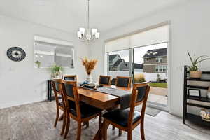 Dining area with a wealth of natural light, hardwood / wood-style floors, and an inviting chandelier