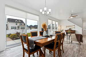 Dining area with light hardwood / wood-style floors and ceiling fan with notable chandelier