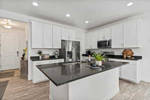 Kitchen featuring white cabinetry and appliances with stainless steel finishes