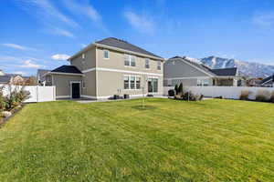 Rear view of house with a fully fenced lawn and a mountain view