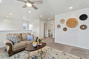 Carpeted living room with ceiling fan