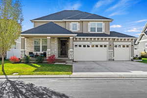 View of front of 2-story home featuring a porch, a garage, and a front yard