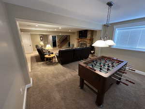 Rec room with a stone fireplace and carpet