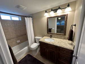 Full bathroom with vanity, tile patterned flooring, toilet, a textured ceiling, and shower / tub combo with curtain