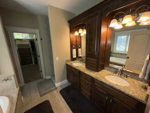 Bathroom featuring tile patterned flooring, a bathtub, a healthy amount of sunlight, and vanity