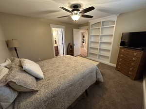 Carpeted bedroom featuring a textured ceiling, connected bathroom, and ceiling fan