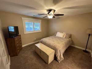 Carpeted bedroom featuring a textured ceiling and ceiling fan