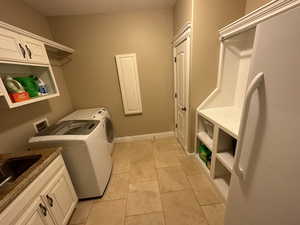 Washroom featuring washing machine and dryer, light tile patterned floors, and cabinets