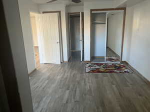 Unfurnished bedroom featuring hardwood / wood-style floors and two closets