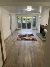 Unfurnished living room featuring hardwood / wood-style flooring and a brick fireplace