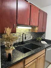 Kitchen featuring sink, tasteful backsplash, stainless steel dishwasher, and dark stone countertops