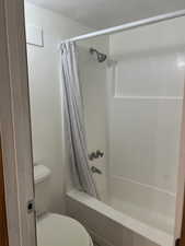 Bathroom with shower / bath combination with curtain and toilet