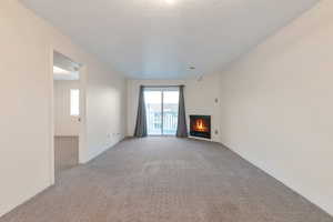 Unfurnished living room with light carpet and a textured ceiling