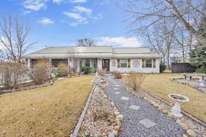 Single story home with brick siding, fence, and a front lawn