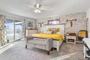 Carpeted bedroom with access to exterior, ceiling fan, and wooden walls