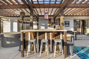 View of patio with exterior bar, a pergola, and a hot tub