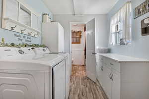 Laundry room with Tile wood-type flooring, washing machine and dryer, and cabinets