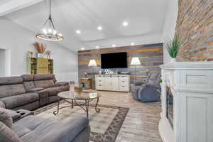 Living room featuring high vaulted ceiling, recessed lighting, an accent wall, light wood finished floors, and an inviting chandelier