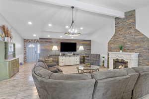 Living area with beam ceiling, recessed lighting, an accent wall, light wood-type flooring, and a warm lit fireplace