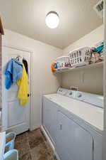 Washroom with a textured ceiling and washing machine and clothes dryer