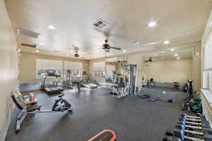 Exercise room with ceiling fan and a textured ceiling