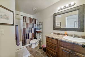 Full bathroom with shower / bath combo with shower curtain, vanity, a textured ceiling, and toilet