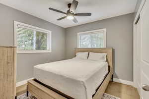 Bedroom with a closet, multiple windows, light colored carpet, and ceiling fan