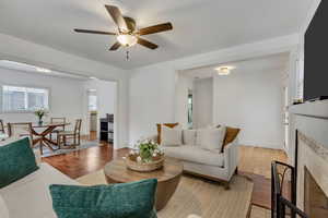 Living room with a fireplace, ceiling fan, and light hardwood / wood-style flooring