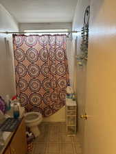 Full bathroom with shower / bath combo with shower curtain, vanity, a textured ceiling, and toilet