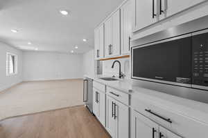 Kitchen featuring white cabinetry, sink, stainless steel appliances, light hardwood / wood-style flooring, and a textured ceiling