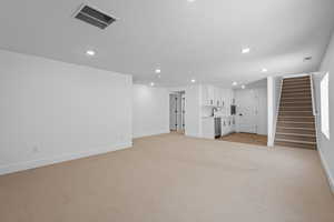 Unfurnished living room featuring light colored carpet and sink