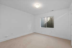 Empty room with light carpet and a textured ceiling