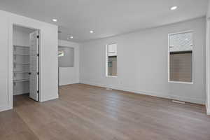 Unfurnished bedroom with a walk in closet and light wood-type flooring