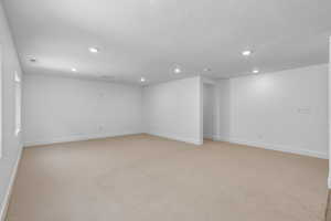 Empty room featuring light carpet and a textured ceiling