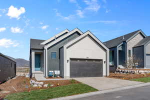 View of front facade with solar panels, a mountain view, and a garage