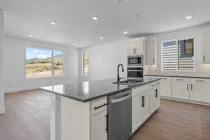 Kitchen with white cabinetry, sink, light wood-type flooring, and appliances with stainless steel finishes