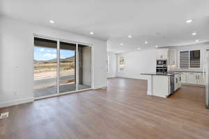 Kitchen featuring sink, stainless steel appliances, an island with sink, light hardwood / wood-style floors, and white cabinets