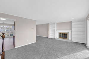 Unfurnished living room with built in shelves, a textured ceiling, a notable chandelier, carpet floors, and a tiled fireplace