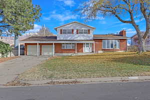 View of front facade featuring a garage and a front lawn