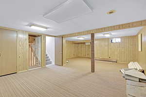 Basement featuring wooden walls, light colored carpet