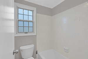 Bathroom featuring toilet and a tub to relax in