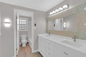 Full bathroom with vanity, bathing tub / shower combination, crown molding, hardwood / wood-style floors, and toilet