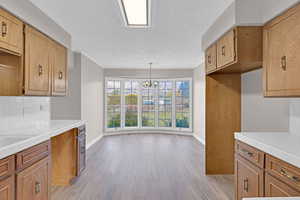 Kitchen featuring ornamental molding, hanging light fixtures, a notable chandelier, and light hardwood / wood-style floors