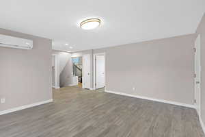 Interior space with a textured ceiling, hardwood / wood-style flooring, and a wall mounted AC