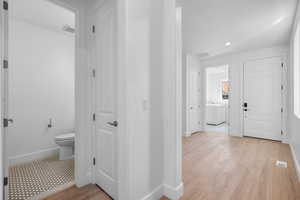 Interior space featuring washer / dryer, hardwood / wood-style flooring, and toilet